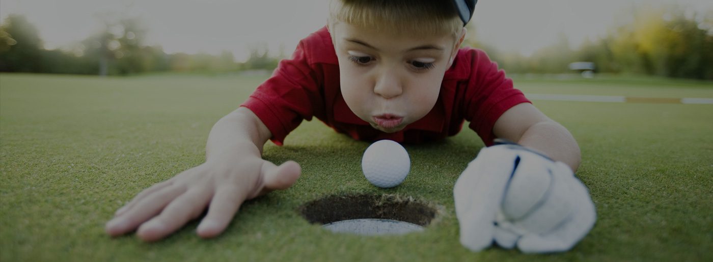 Little boy blowing golf ball